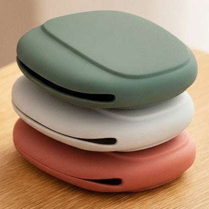 Stack of colorful wireless earbuds cases on a wooden surface with a blurred background